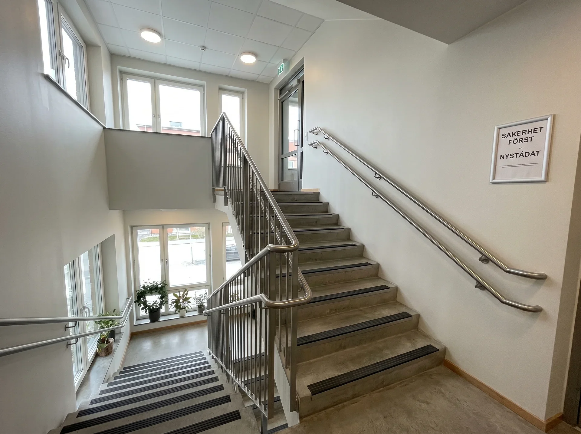 Ljust trapphus med rostfria räcken och skylt om städning.